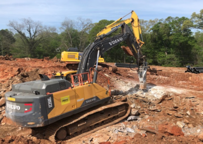 Excavator hammering rock on the site of the future new housing units