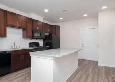 kitchen with stone countertops, black appliances, and cherry-finish cabinetry inside of a residence at The View at NoDA apartments in Athens Georgia