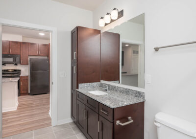 bathroom vanity and linen cabinet with kitchen view in the background at The View at NoDA apartments in Athens Georgia