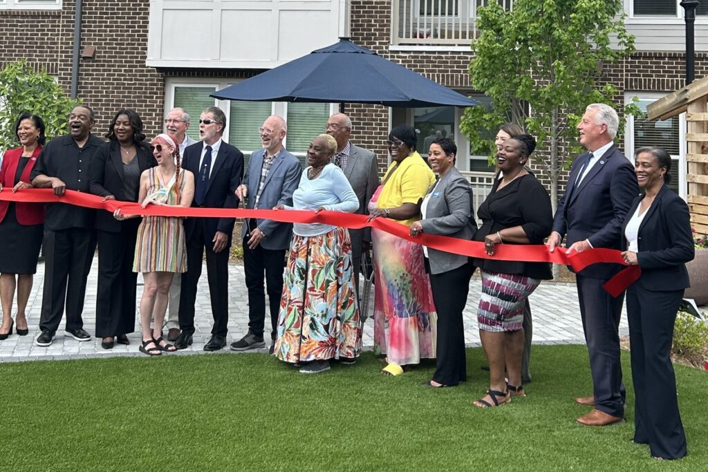 a group of happy people holding a red ribbon as part of the ribbon-cutting ceremony at The View at NoDA apartments in Athens Georgia