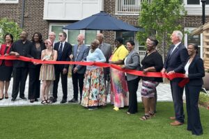 a group of happy people holding a red ribbon as part of the ribbon-cutting ceremony at The View at NoDA apartments in Athens Georgia